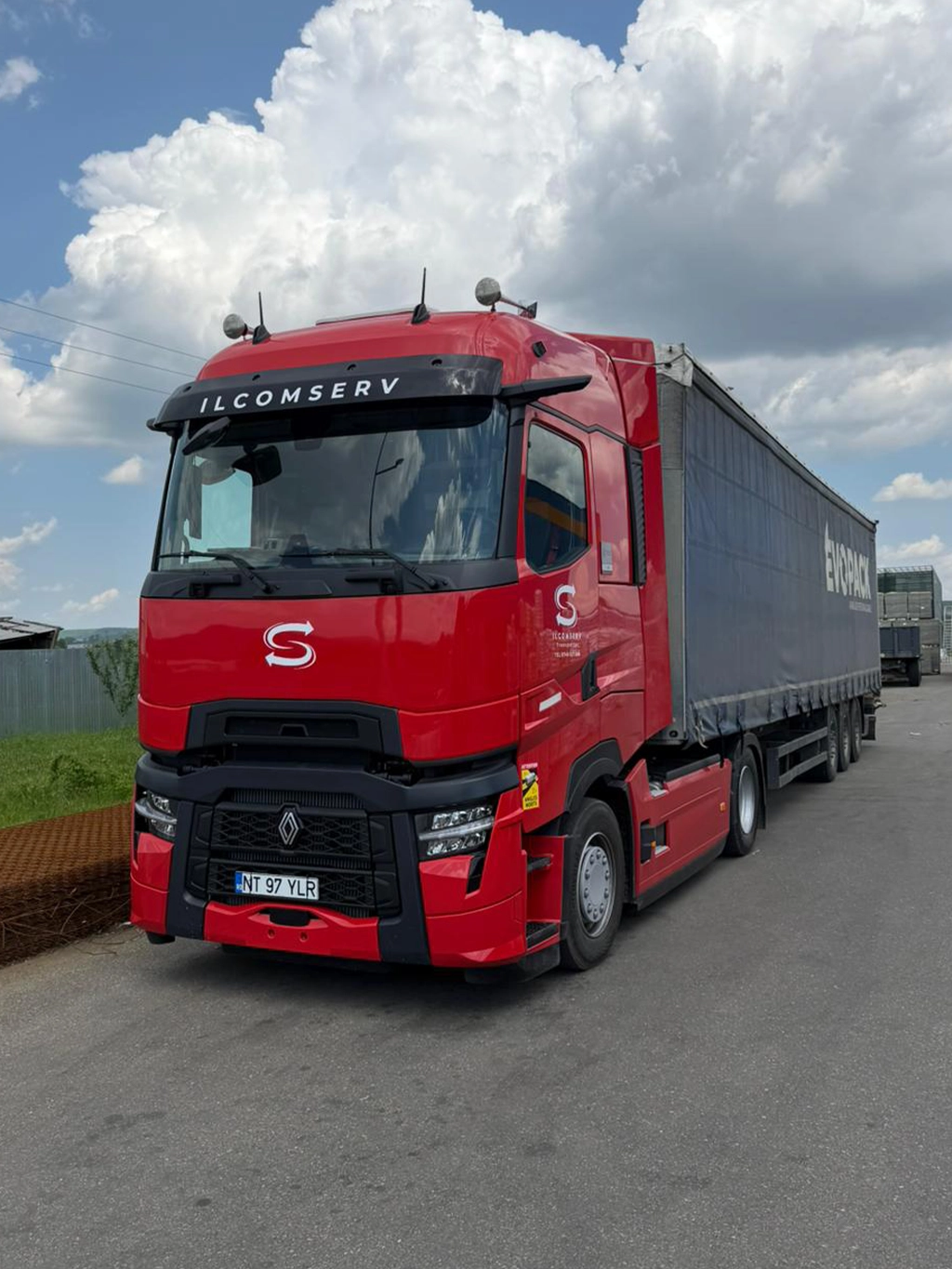 Camion Renault modern si semiremorca cu prelata aflate in curte unei firme